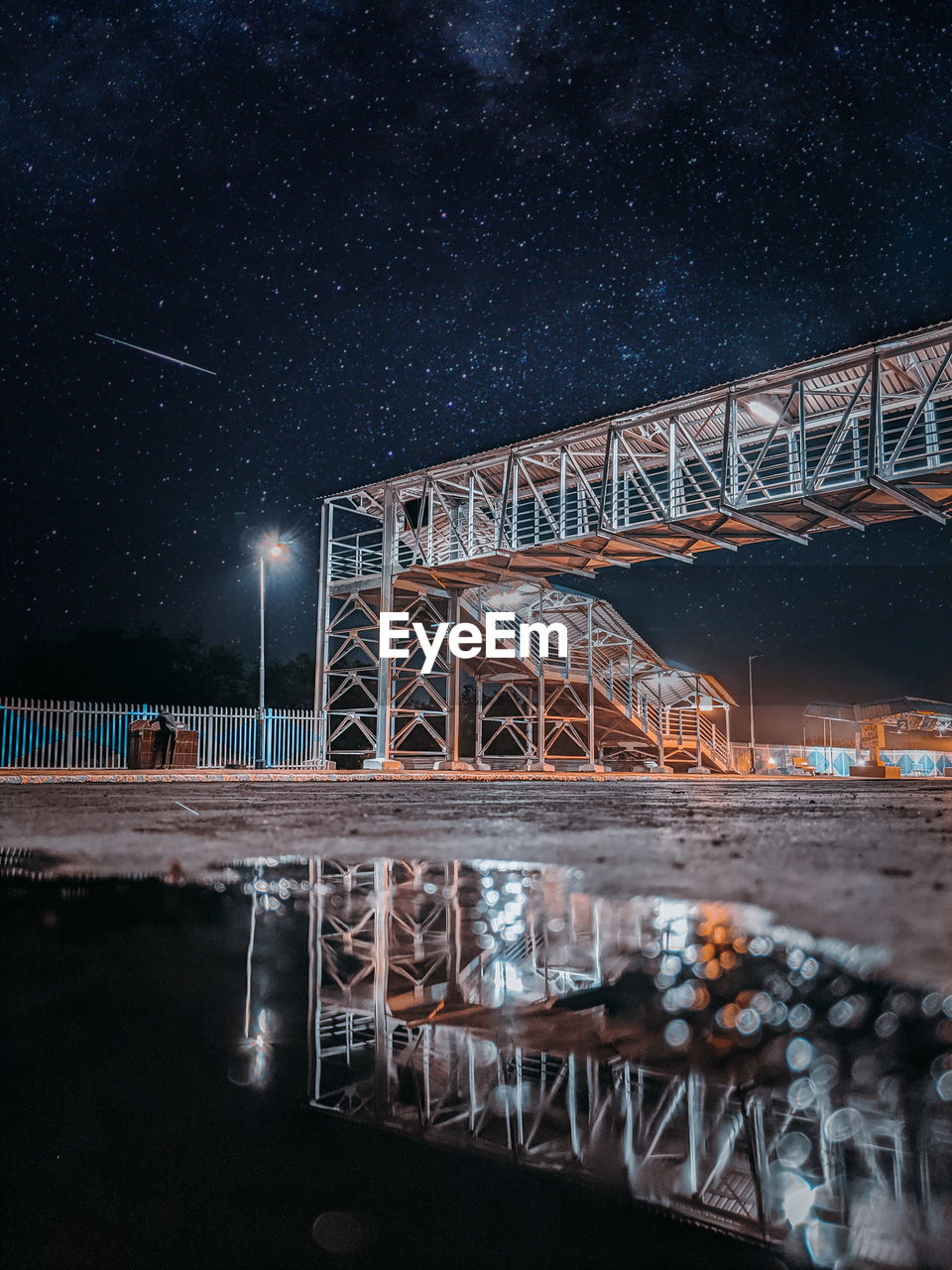 Reflective image of a crossover in railway station with the sky full of stars