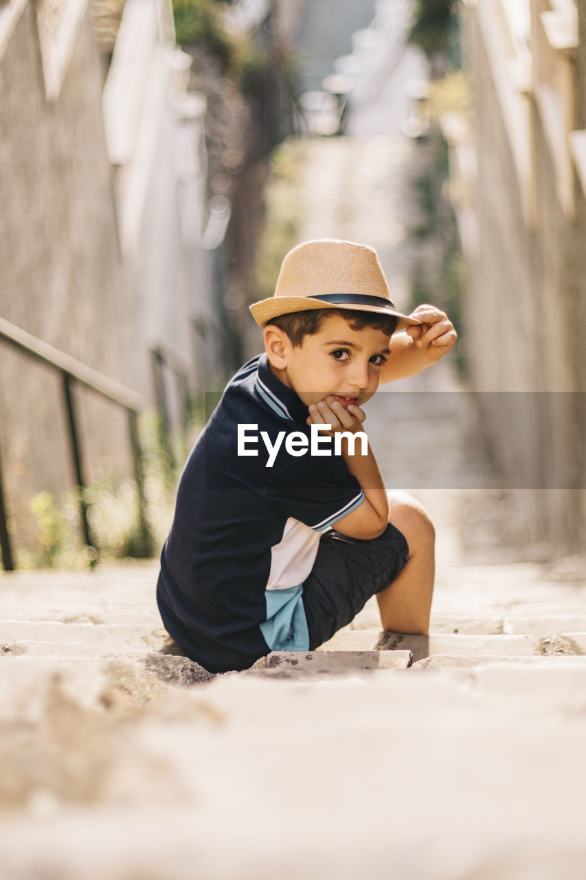 Portrait of boy wearing hat sitting on steps