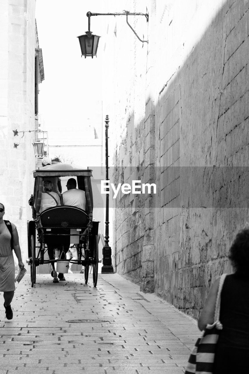 People on street by building in city