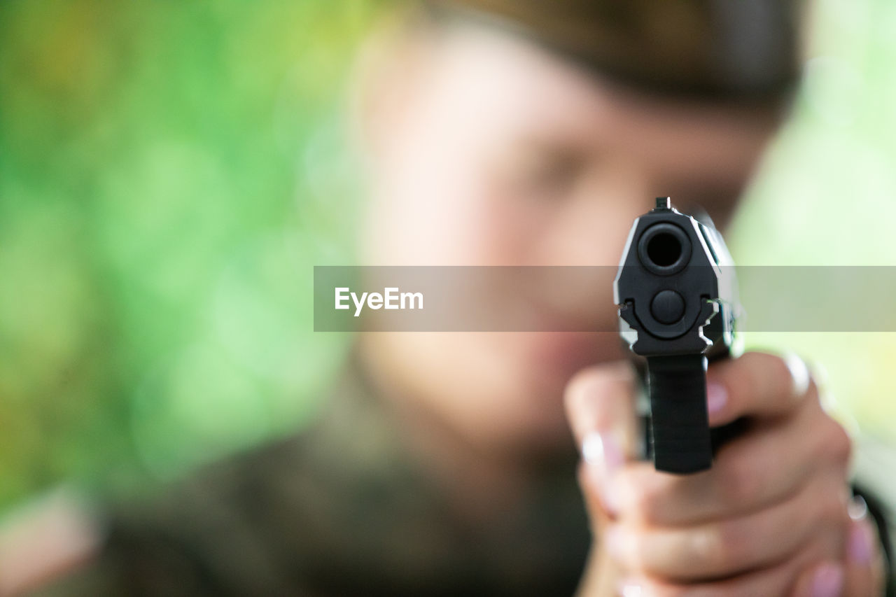 The lady soldier aims straight at the camera with a short gun.