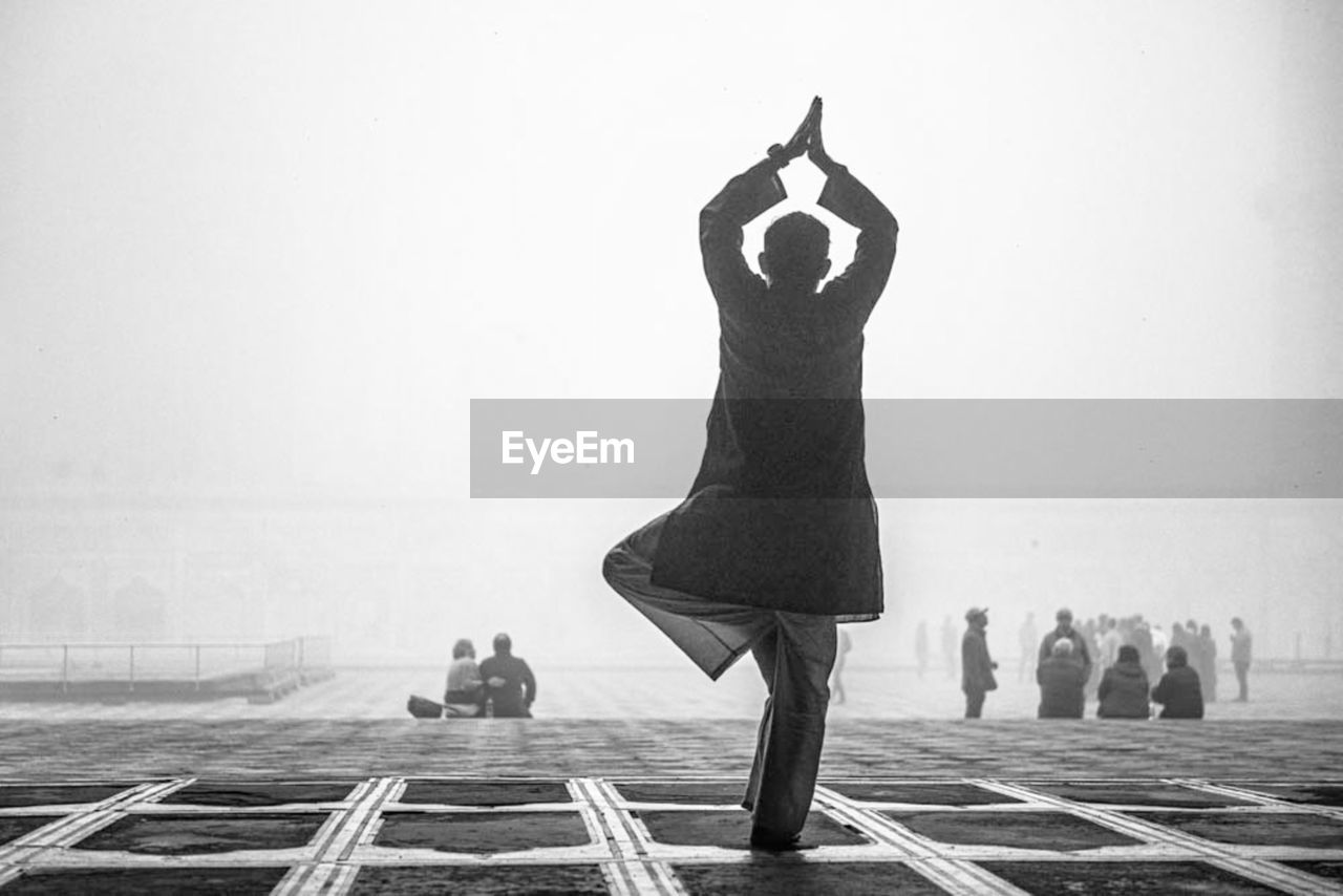 REAR VIEW OF MAN AND WOMAN STANDING AGAINST THE SKY