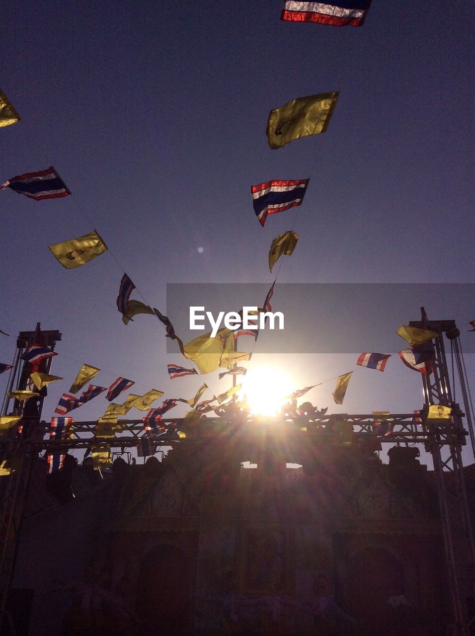 Low angle view of bunting flags against sky at sunset