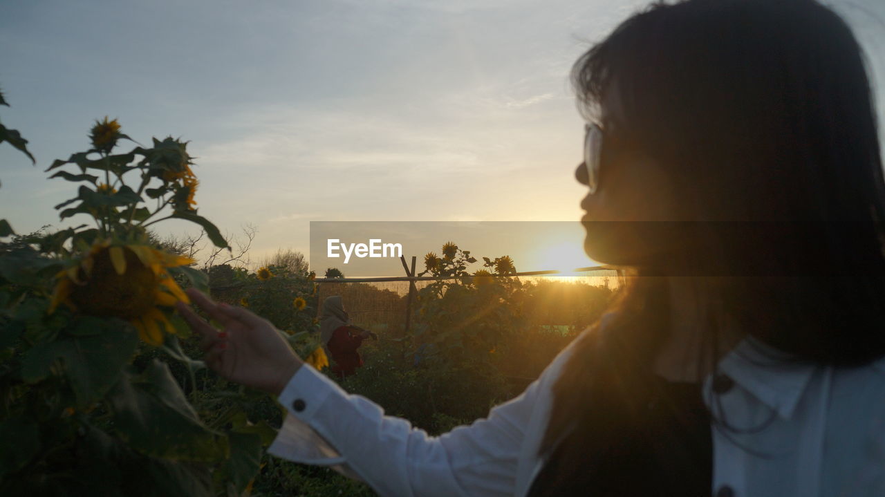 Woman standing by sunflower against sky