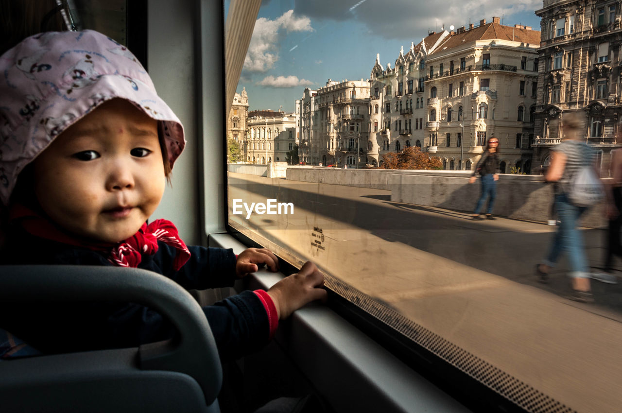 Close-up portrait of baby boy sitting by window in bus