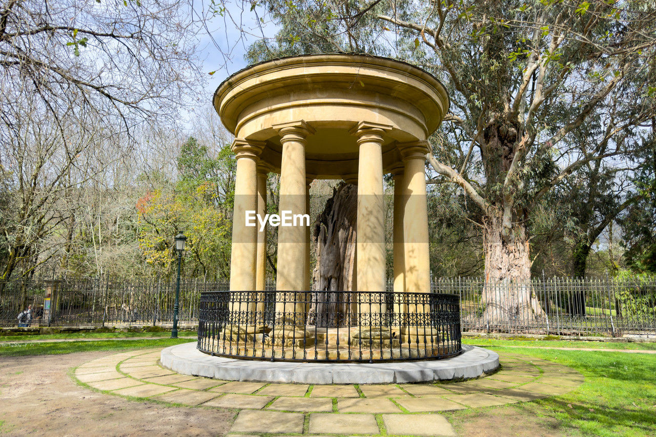 tree, plant, architecture, nature, built structure, architectural column, the past, history, no people, day, park, estate, travel destinations, park - man made space, building exterior, grass, outdoors, sky, travel, city, memorial, garden, tourism, landmark, growth