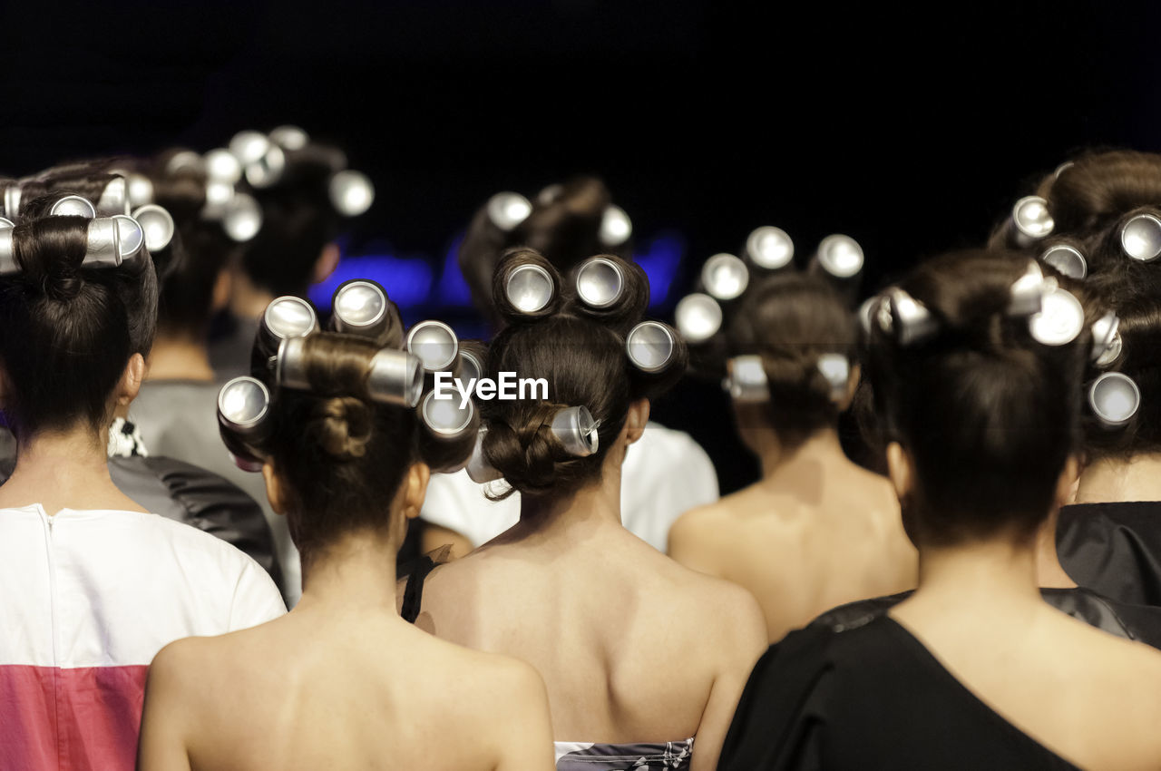 Rear view of women wearing hair curlers at fashion show