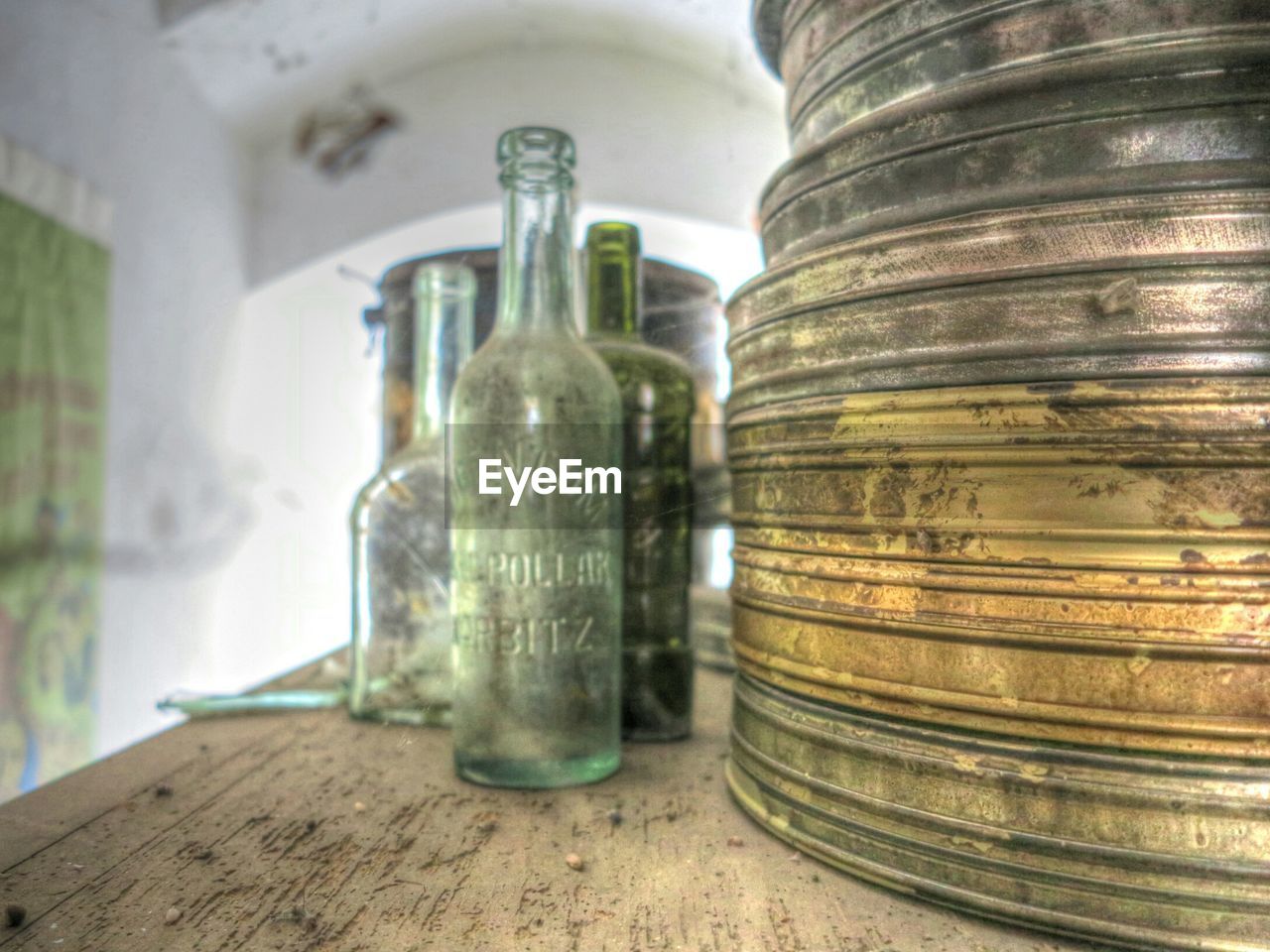 Old metal container and glass bottles on table