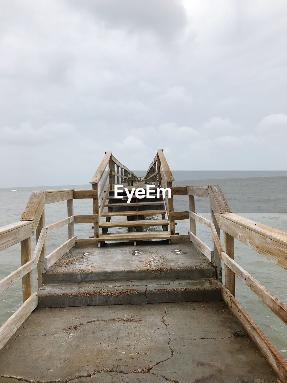 Wooden pier on beach against sky