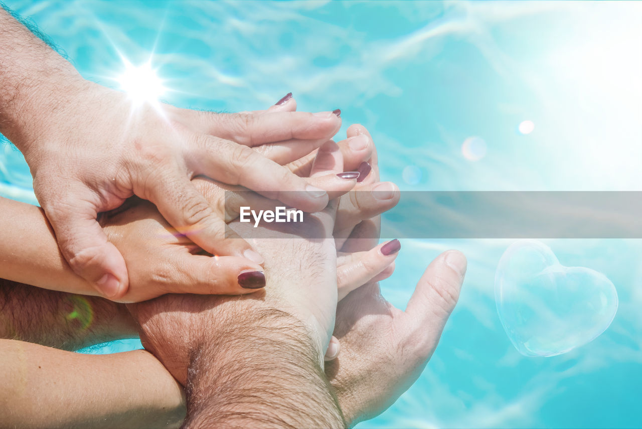High angle view of hands stacking over swimming pool