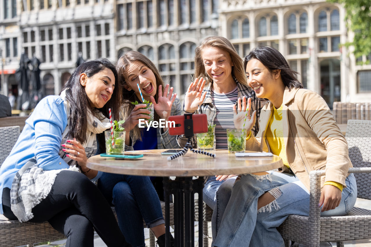 friends using mobile phone while sitting at outdoor cafe