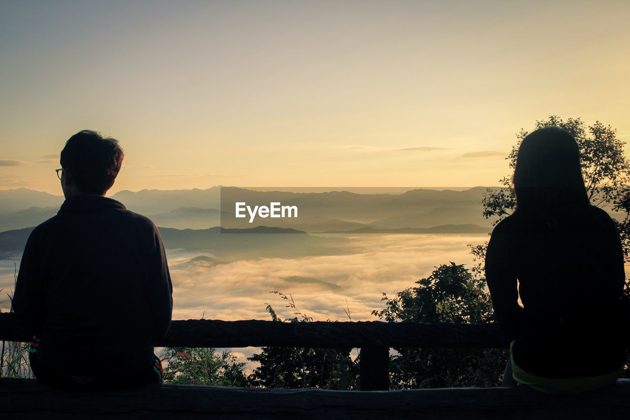 REAR VIEW OF MAN LOOKING AT SUNSET