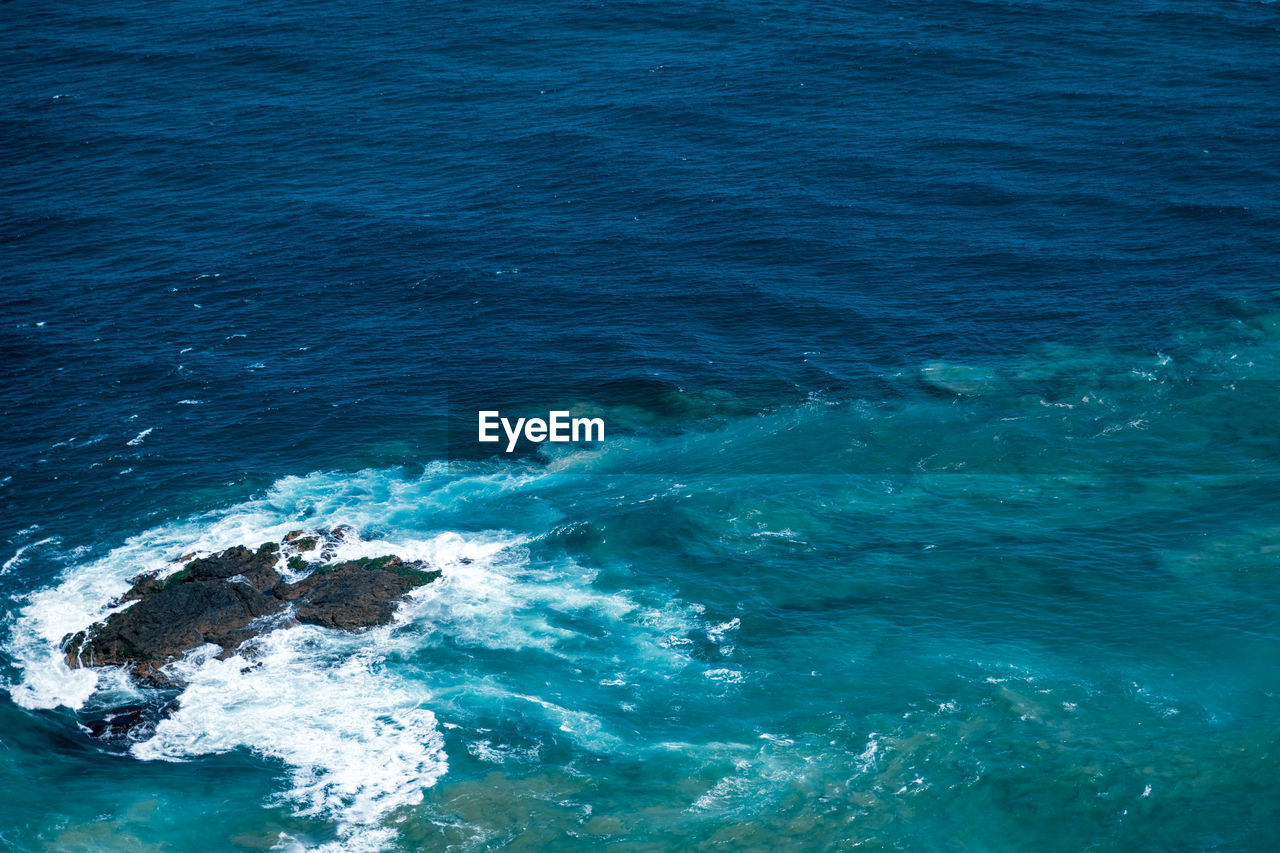 High angle view of sea with waves crashing against rocks