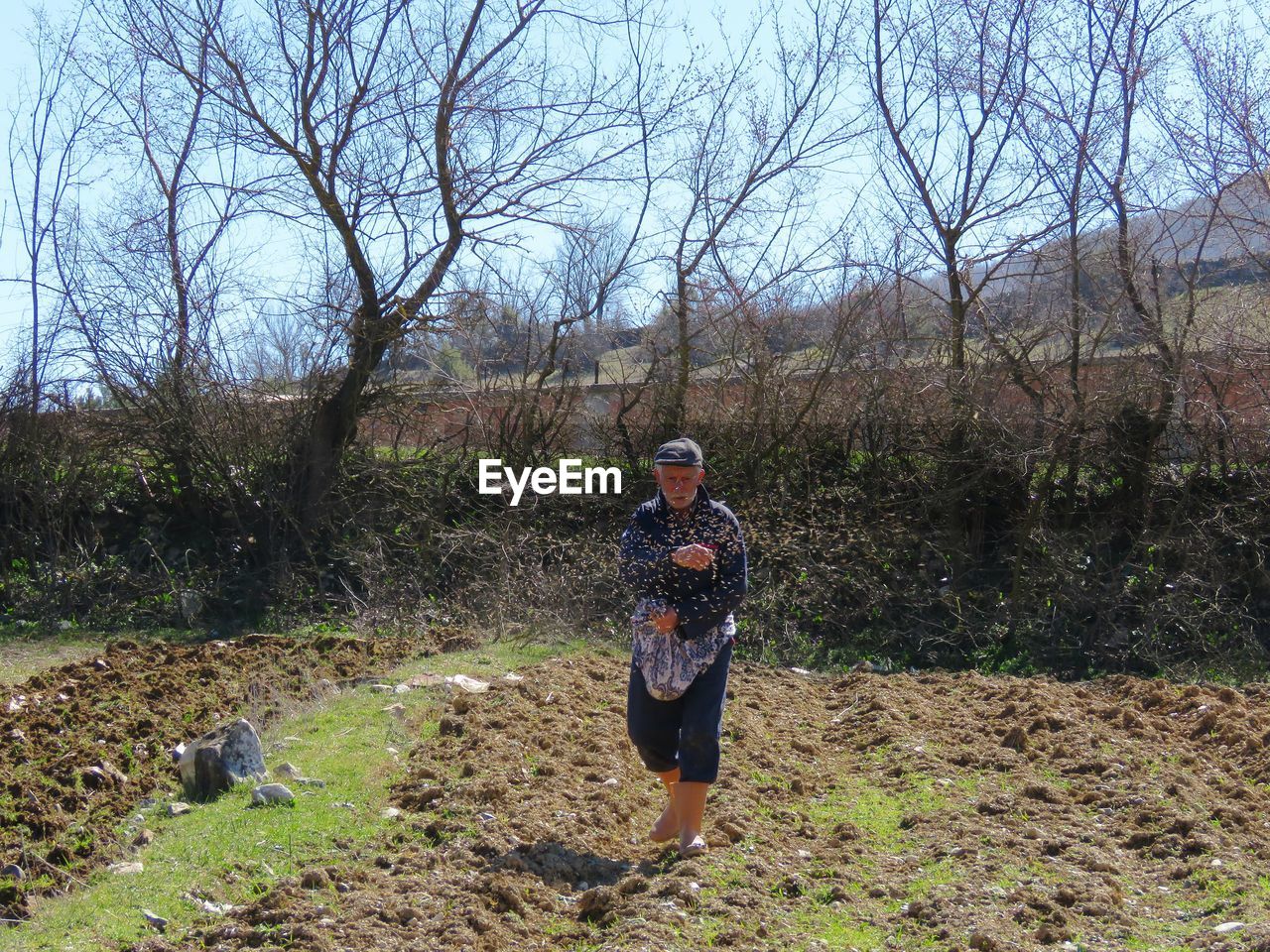 Man throwing seeds while standing on agricultural field