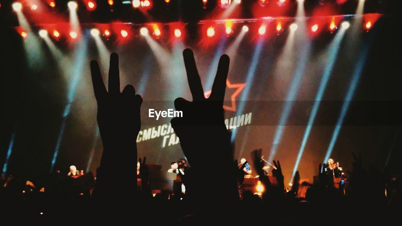 Cropped hands showing peace sign at music concert