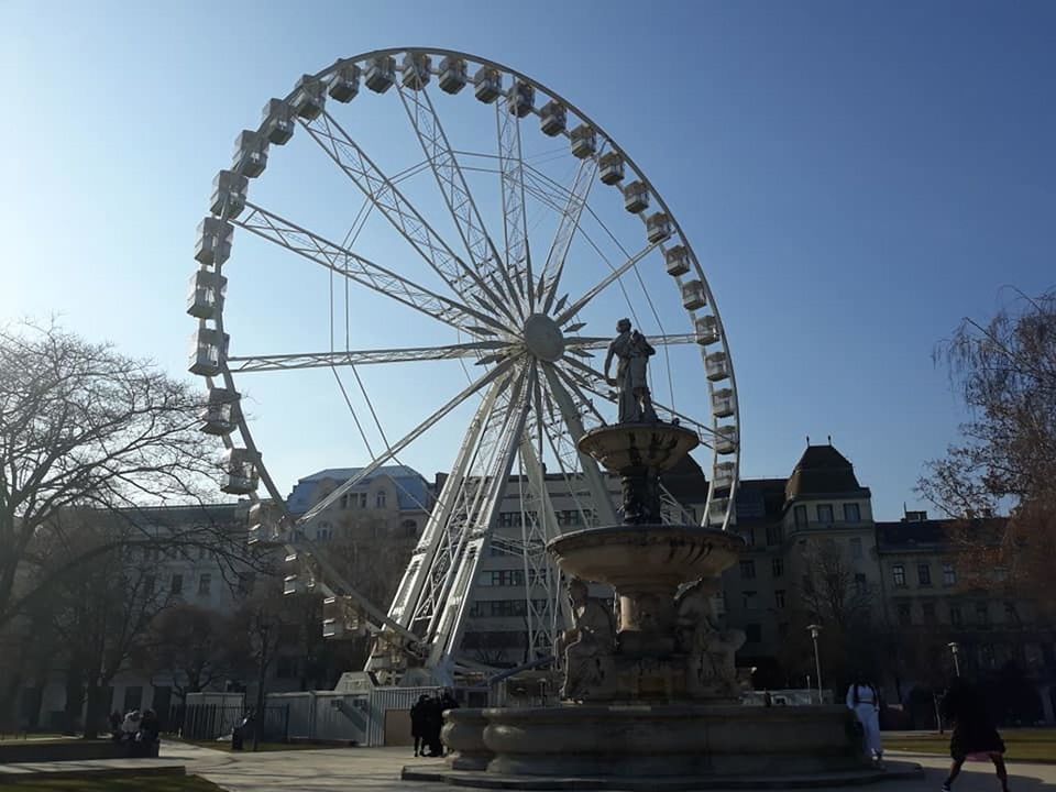 ferris wheel, architecture, amusement park ride, amusement park, arts culture and entertainment, sky, built structure, travel destinations, nature, landmark, tree, city, travel, building exterior, tourism, park, clear sky, outdoors, recreation, leisure activity, history, day, the past