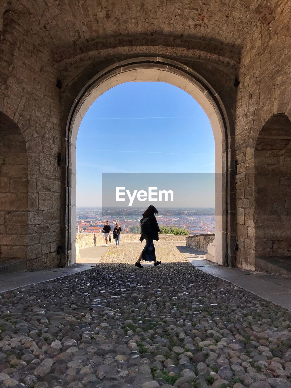 People walking at historic building against sky