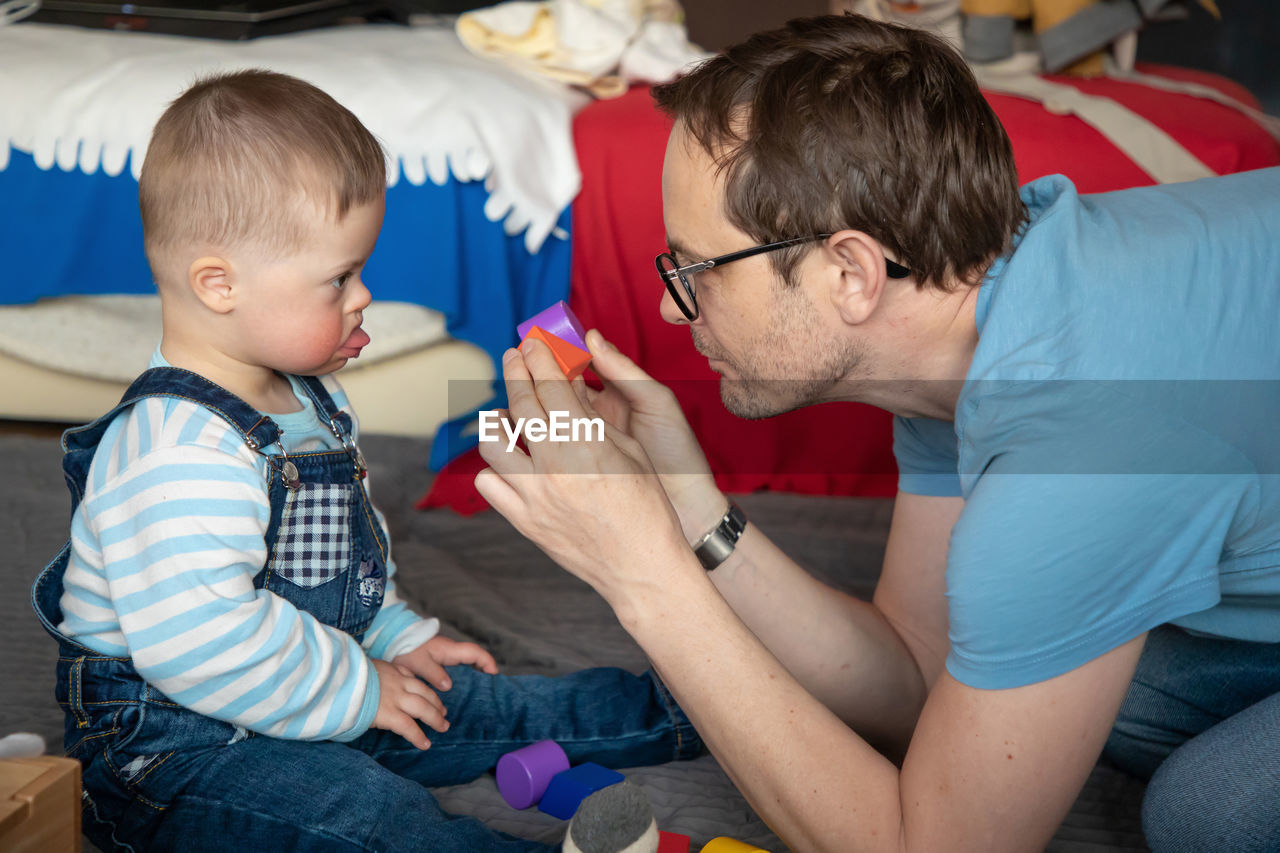 Side view of father playing with toddler son at home