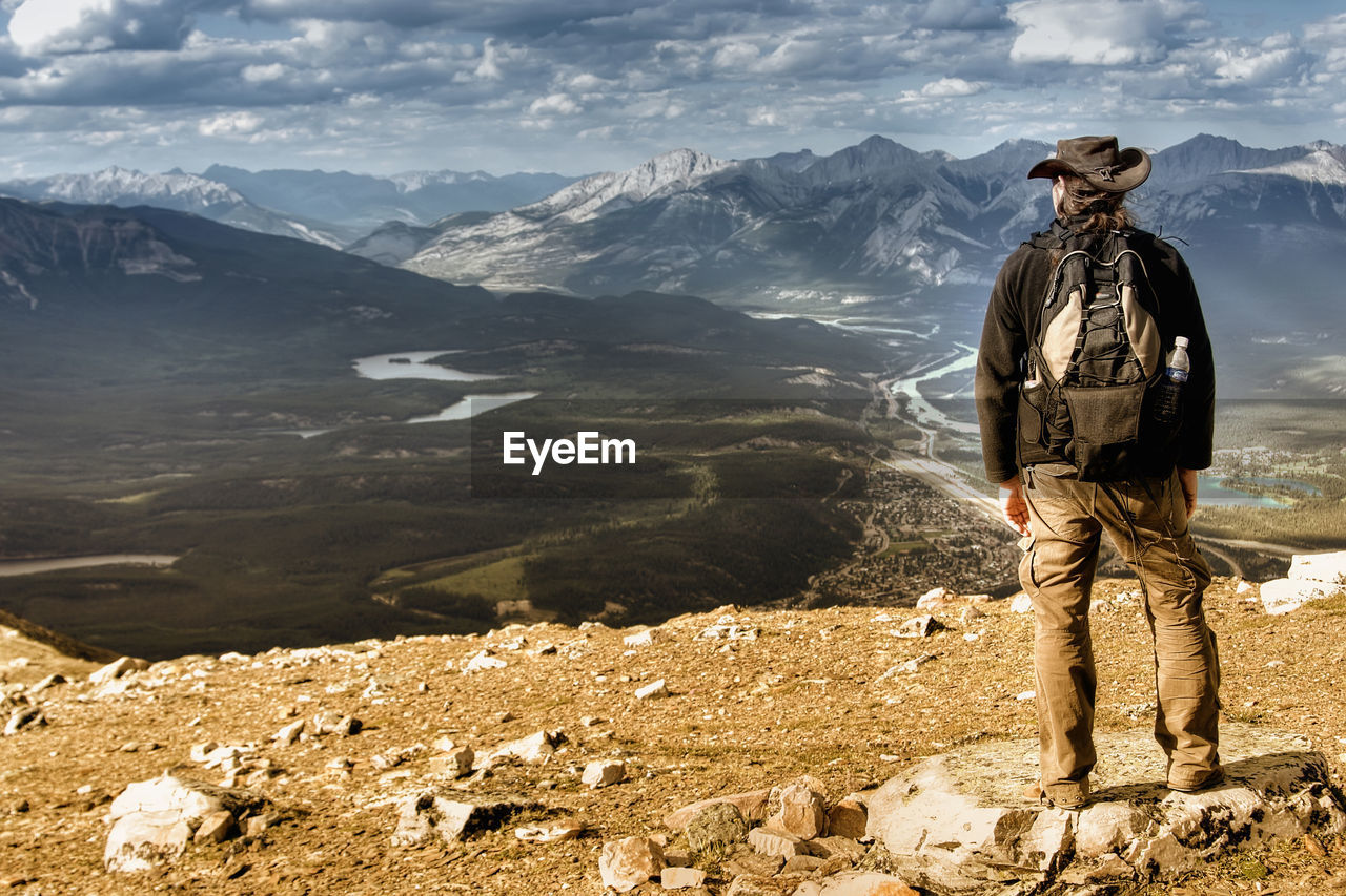 Rear view of man standing on mountain against sky