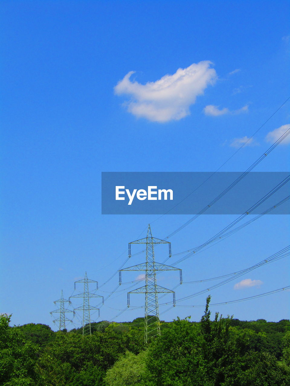 Low angle view of electricity pylon against blue sky