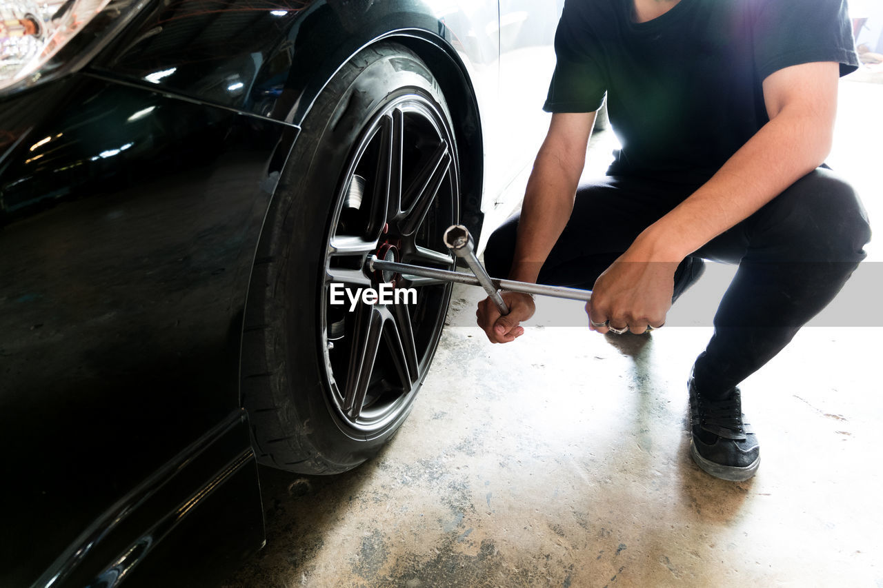 Low section of mechanic changing car tire