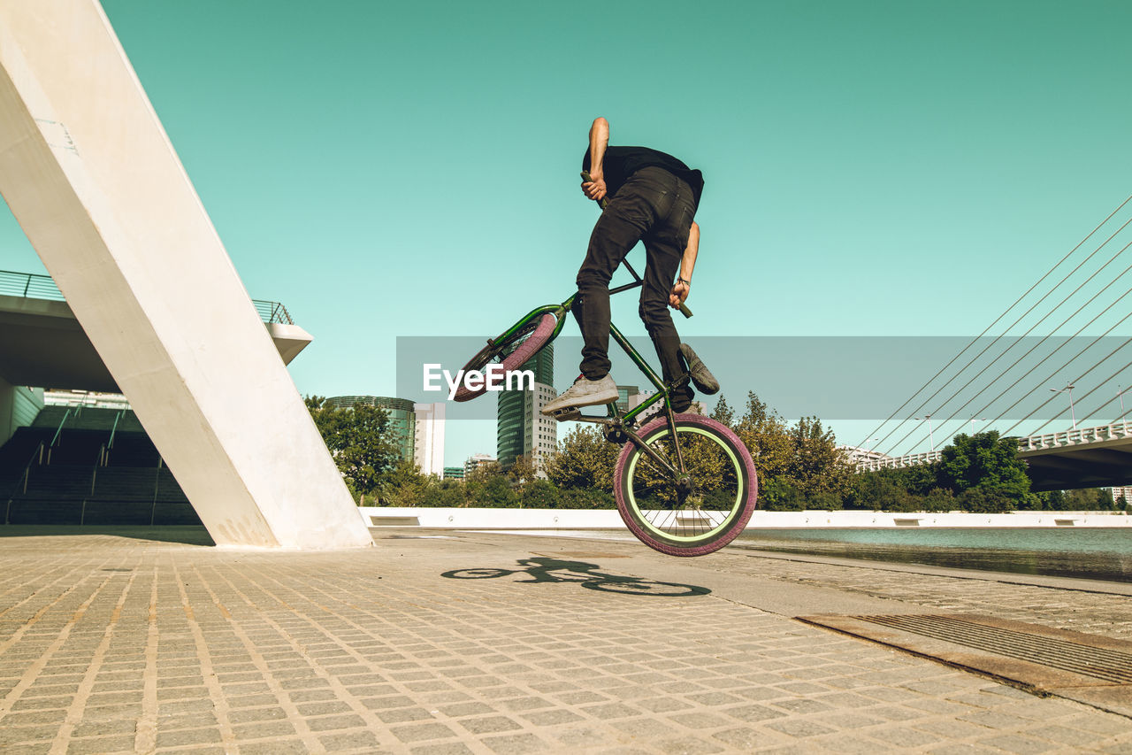 Man riding bmx cycle on footpath in city