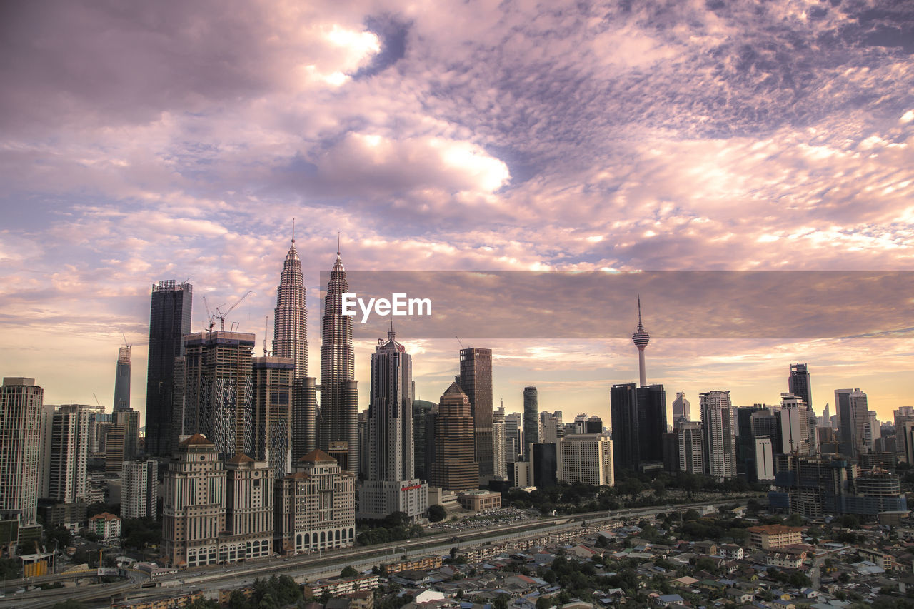 Modern buildings in city against cloudy sky