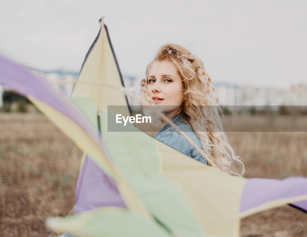 Portrait of woman holding kite on field