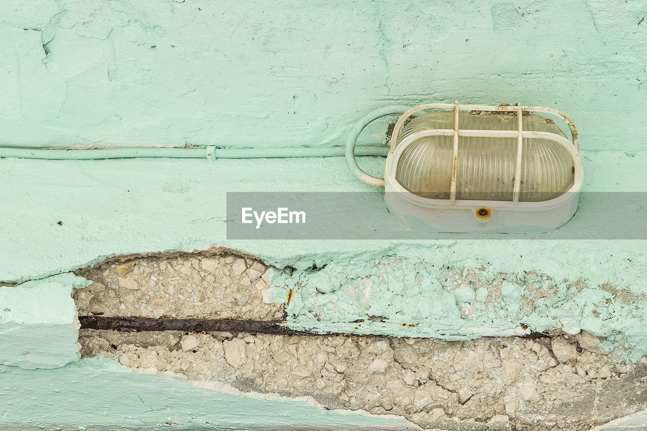 Low angle view of lighting equipment on weathered wall