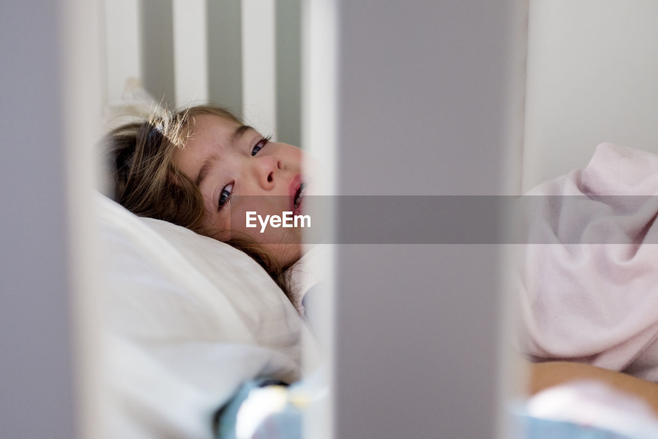 Portrait of baby girl crying while lying in crib at home