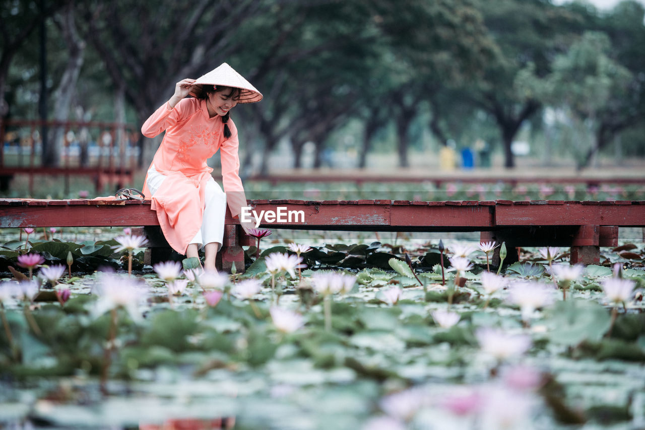 REAR VIEW OF WOMAN WITH UMBRELLA ON RAILROAD TRACK