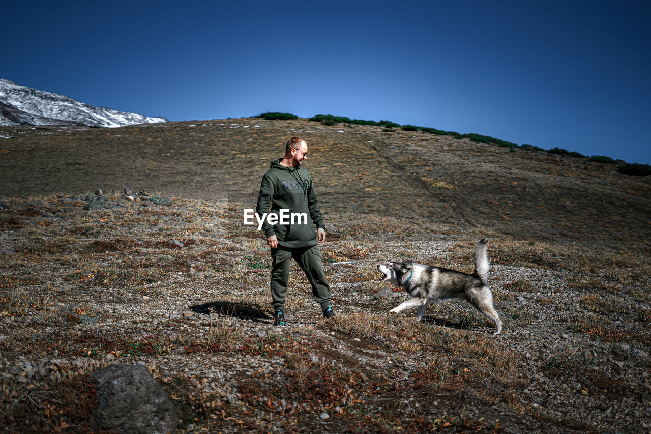 Full length of man with dog in mountains against clear sky