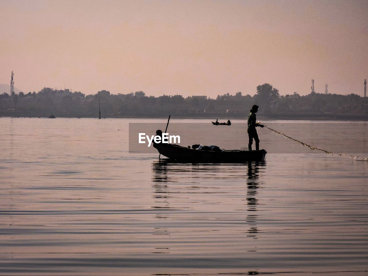 SILHOUETTE MAN IN BOAT ON SEA AGAINST SKY