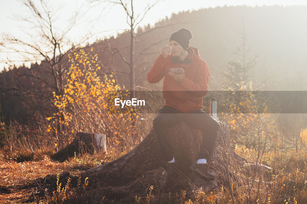 Tourist sitting on a stump eating porridge at sunrise. beskydy mountains, czech republic
