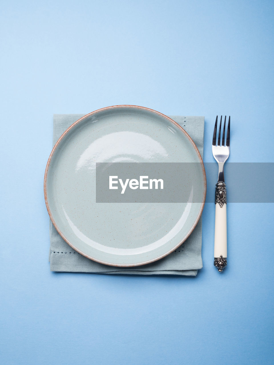 Blue pastel ceramic dish on napkin with fork. abstract food, tableware crockery concept