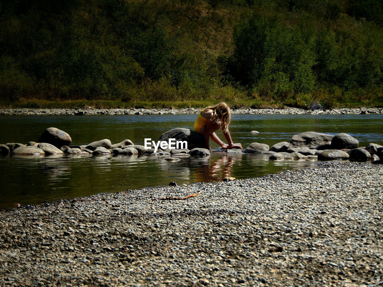 Side view of girl sitting on rocks at elbow river