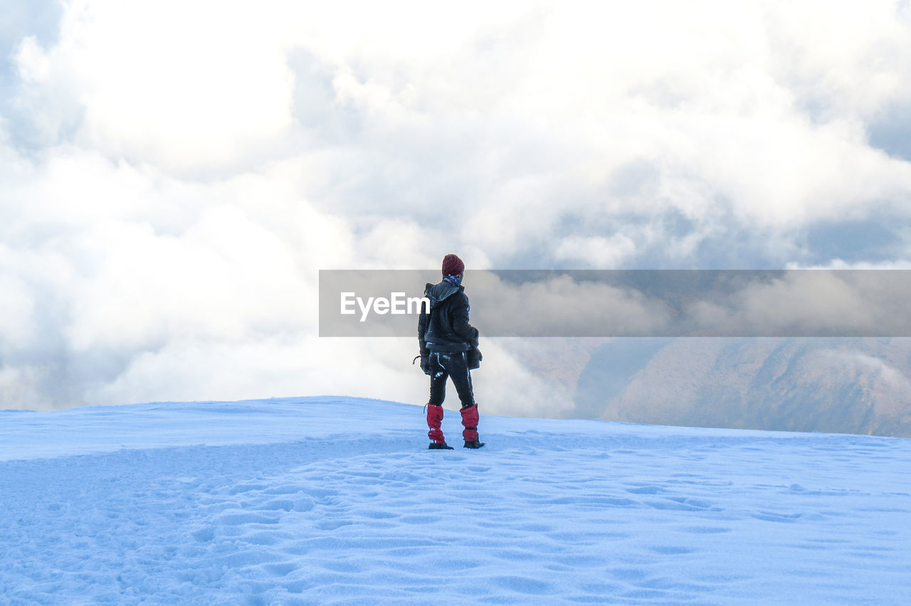 Rear view of man standing on snow against sky