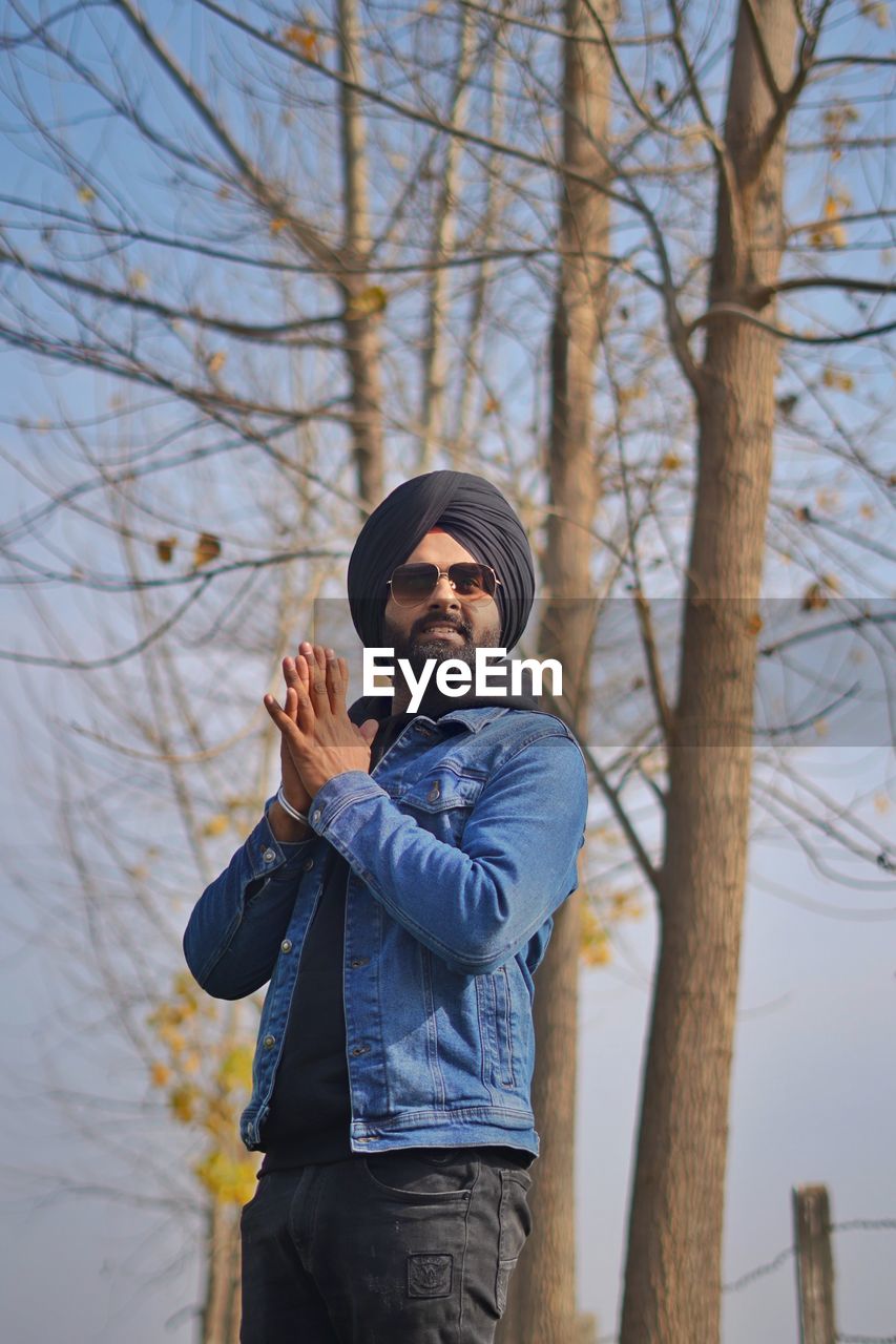 Young man wearing turban standing by bare trees