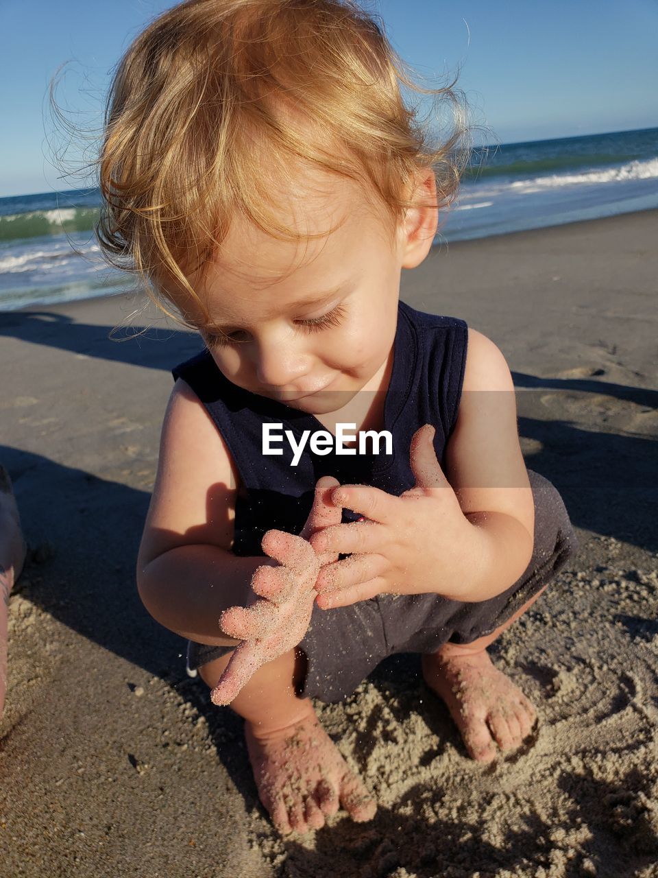 Cute boy playing with sand at beach