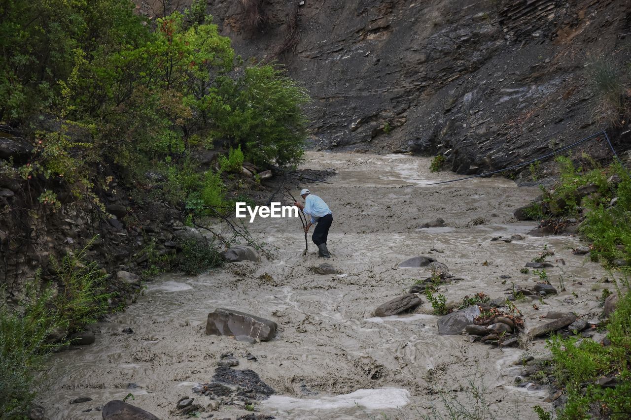 Rear view of man walking on mud by mountain