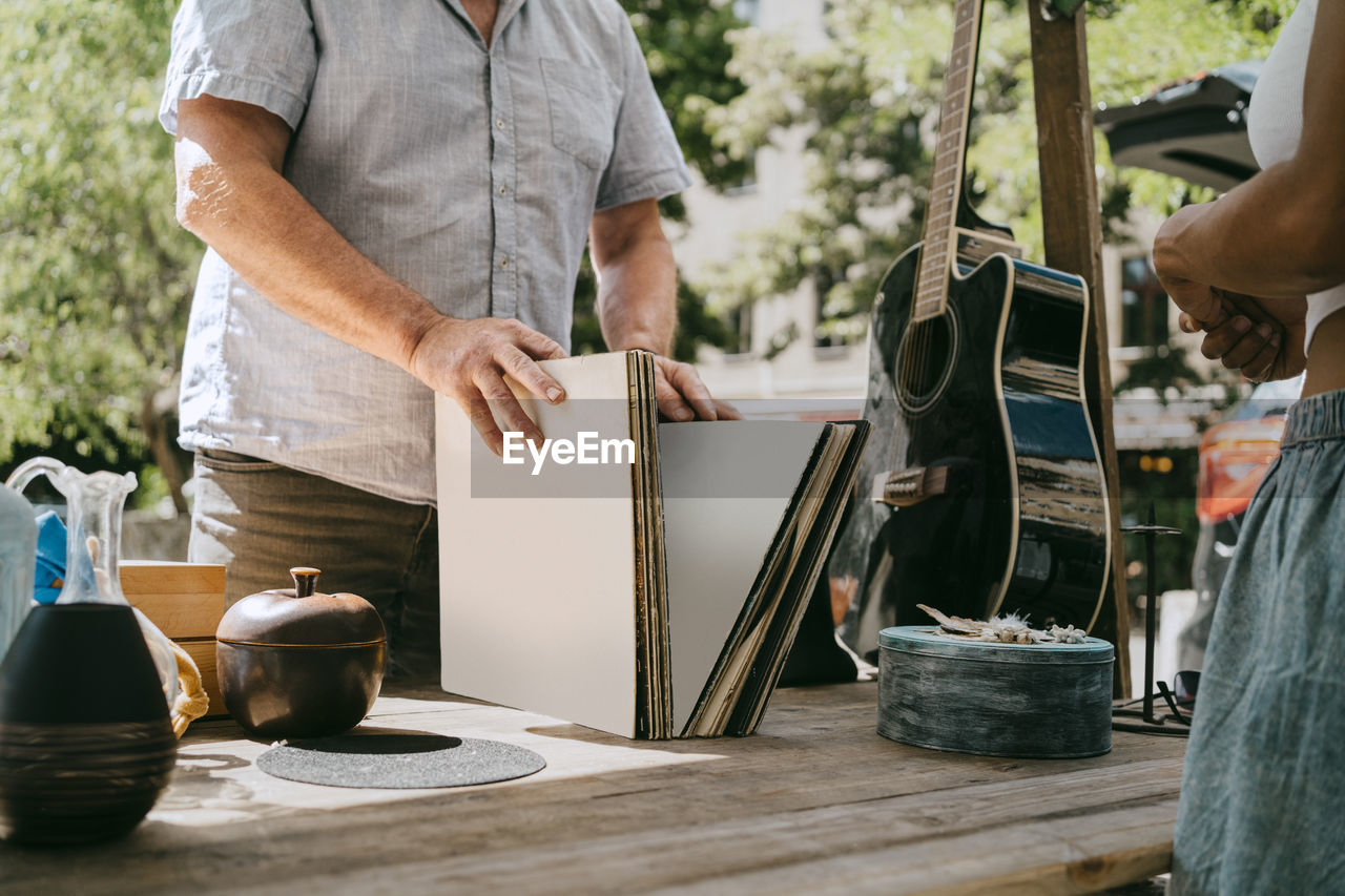 Midsection of male customer buying records at flea market