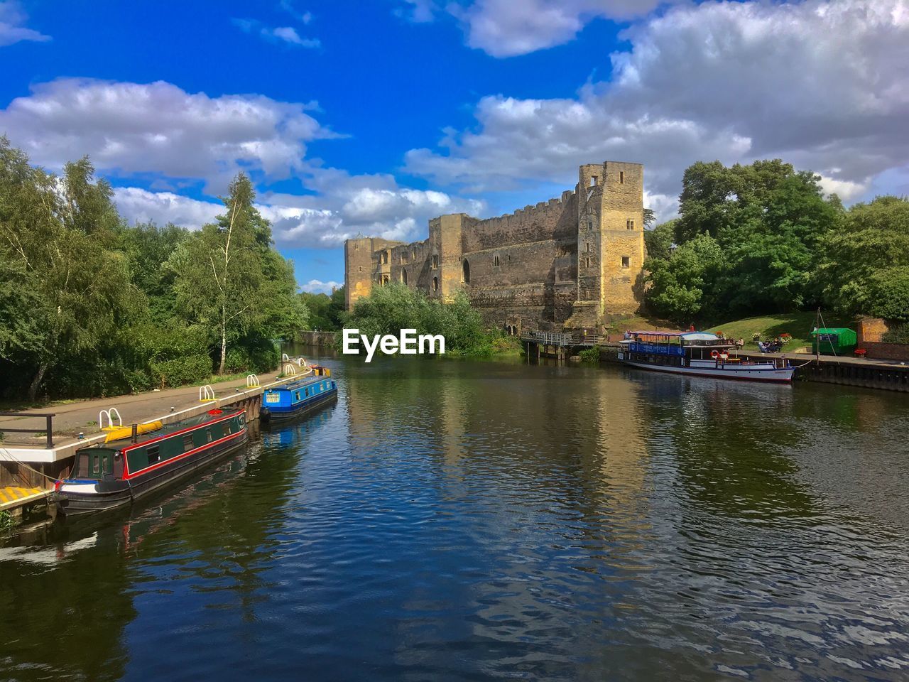 BOATS IN RIVER AGAINST CLOUDY SKY