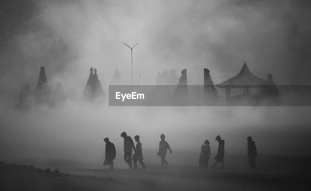 Silhouette children and buildings in foggy weather