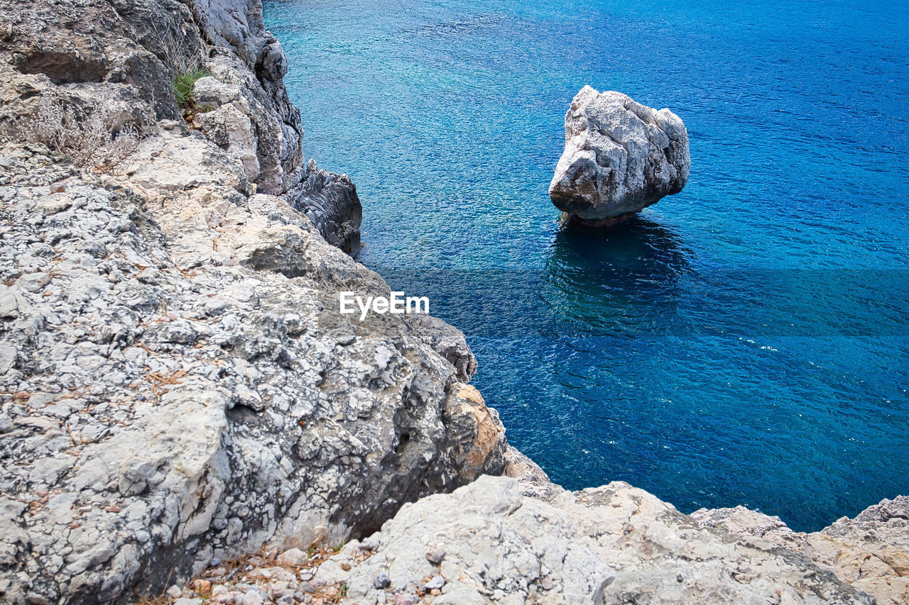 HIGH ANGLE VIEW OF ROCK FORMATIONS ON SEA SHORE