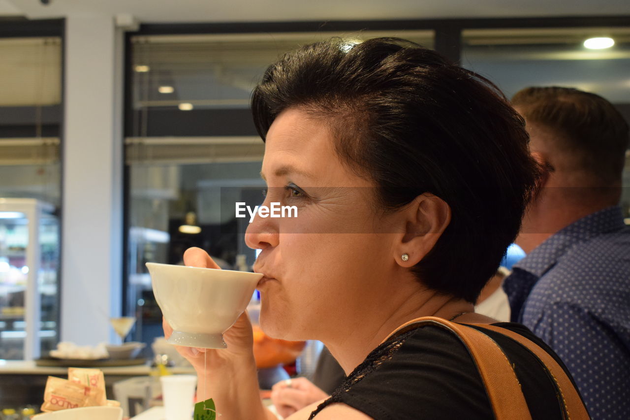 Close-up of woman having drink while sitting in restaurant