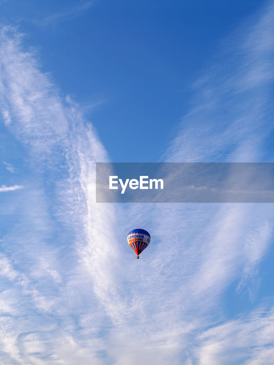 sky, blue, flying, mid-air, cloud, air vehicle, adventure, balloon, transportation, hot air balloon, nature, low angle view, aircraft, extreme sports, sports, vehicle, motion, day, joy, wing, environment, hot air ballooning, outdoors, mode of transportation, travel, parachute, multi colored, leisure activity, wind, no people, exhilaration, beauty in nature, toy, air sports, sunlight