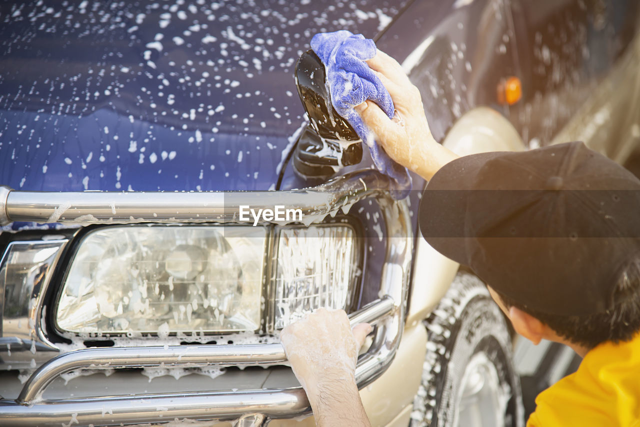 Close-up of man washing car