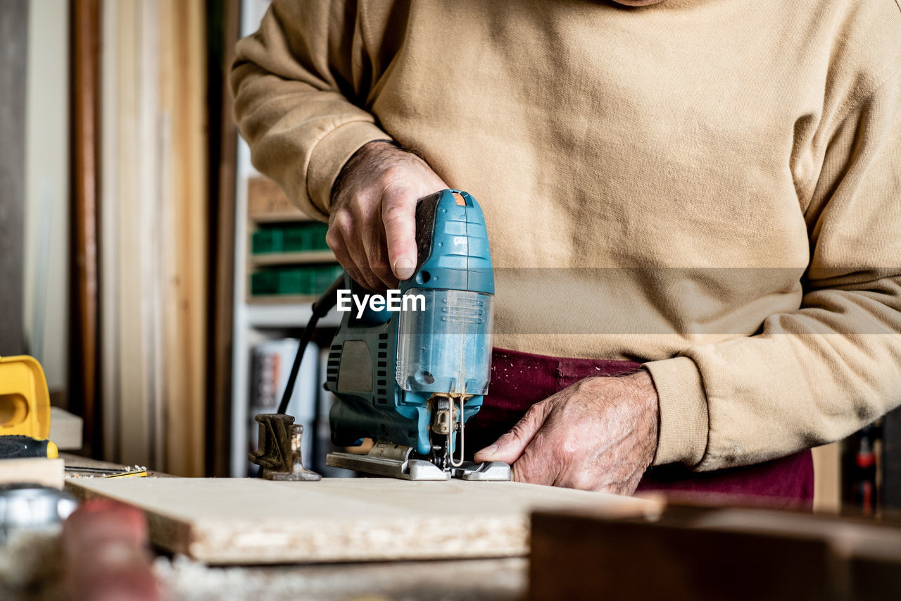 Midsection of carpenter working on wood