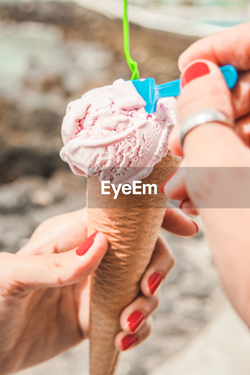 Cropped hand of woman holding ice cream cone outdoors
