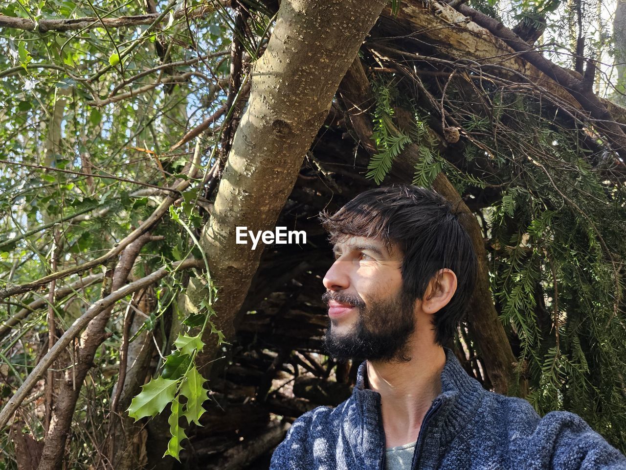 tree, plant, one person, forest, leisure activity, young adult, nature, beard, jungle, casual clothing, headshot, adult, natural environment, men, portrait, growth, facial hair, spring, lifestyles, land, looking, day, looking away, trunk, tree trunk, outdoors, standing, woodland, front view, flower, rainforest, smiling, beauty in nature, tranquility, person, relaxation, looking up, green, branch