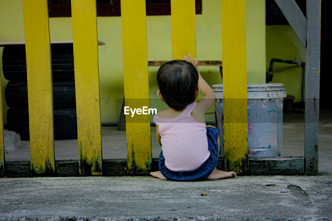 FULL LENGTH REAR VIEW OF GIRL ON YELLOW CART